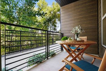 A wooden table with a flower arrangement on it sits on a balcony.